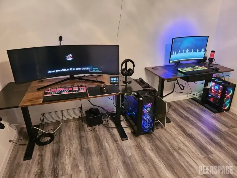 A room with two computer desks and two computer monitors.