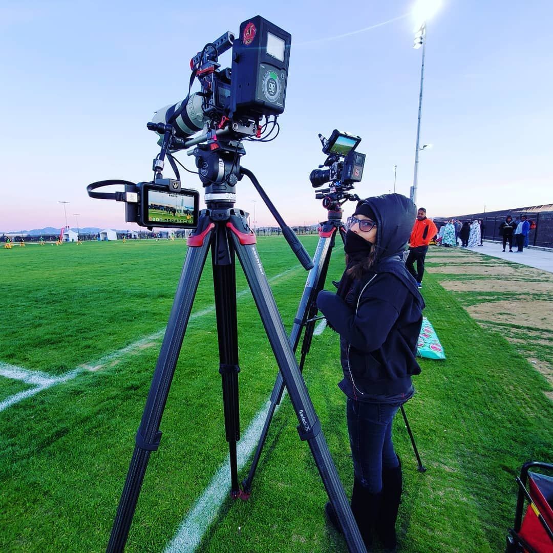 A woman is standing in front of a camera on a tripod