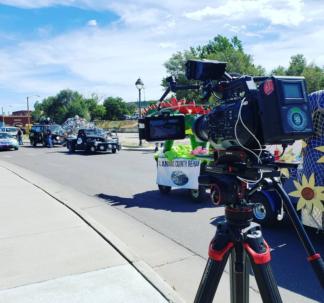 A camera on a tripod is recording a parade