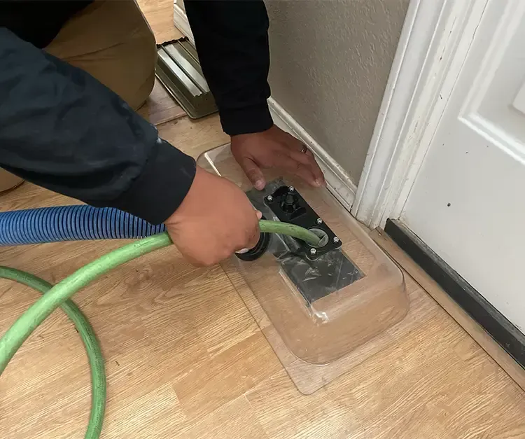 A man is using a green hose to clean a door.