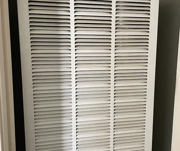 A white air filter is sitting on a wall next to a door.