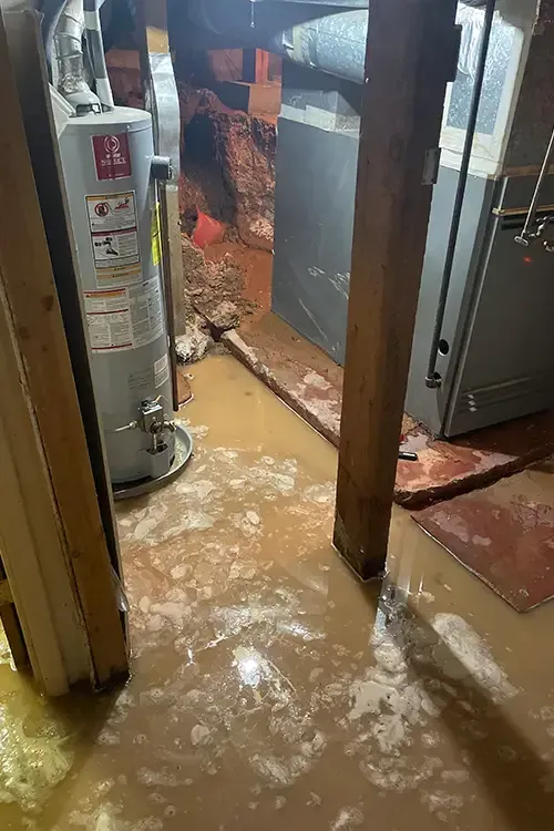 A flooded basement with a water heater and a refrigerator.