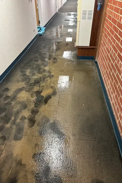 A hallway with a brick wall and a mop on the floor.