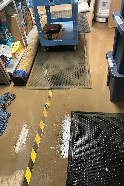 A flooded room with a yellow and black striped tape on the floor.