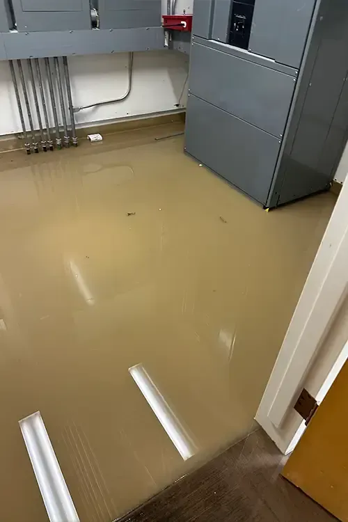 A room with a flooded floor and a refrigerator.