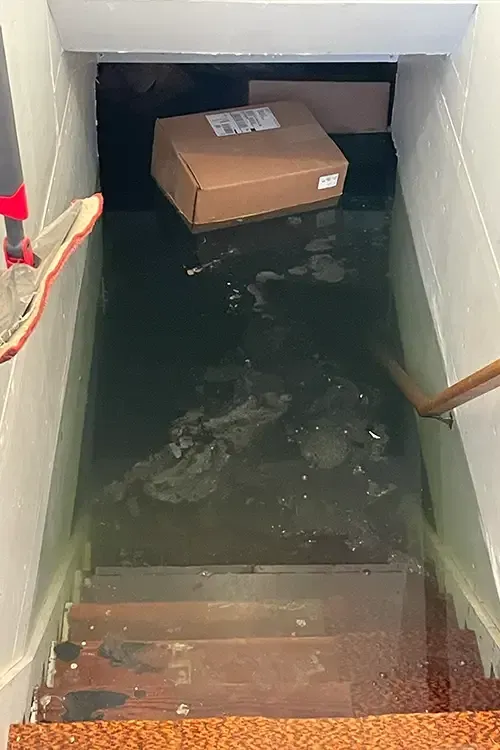 A cardboard box is floating in a flooded basement.