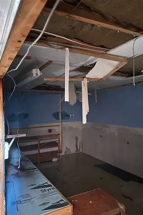 A room with a broken ceiling and a table in it.