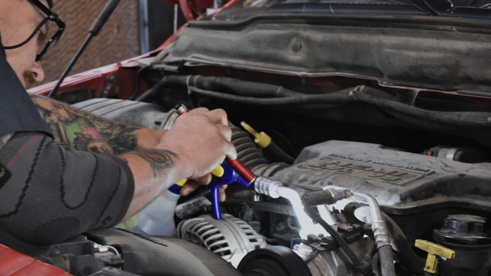 Auto technician inspecting under the hood of a vehicle during a pre purchase inspection