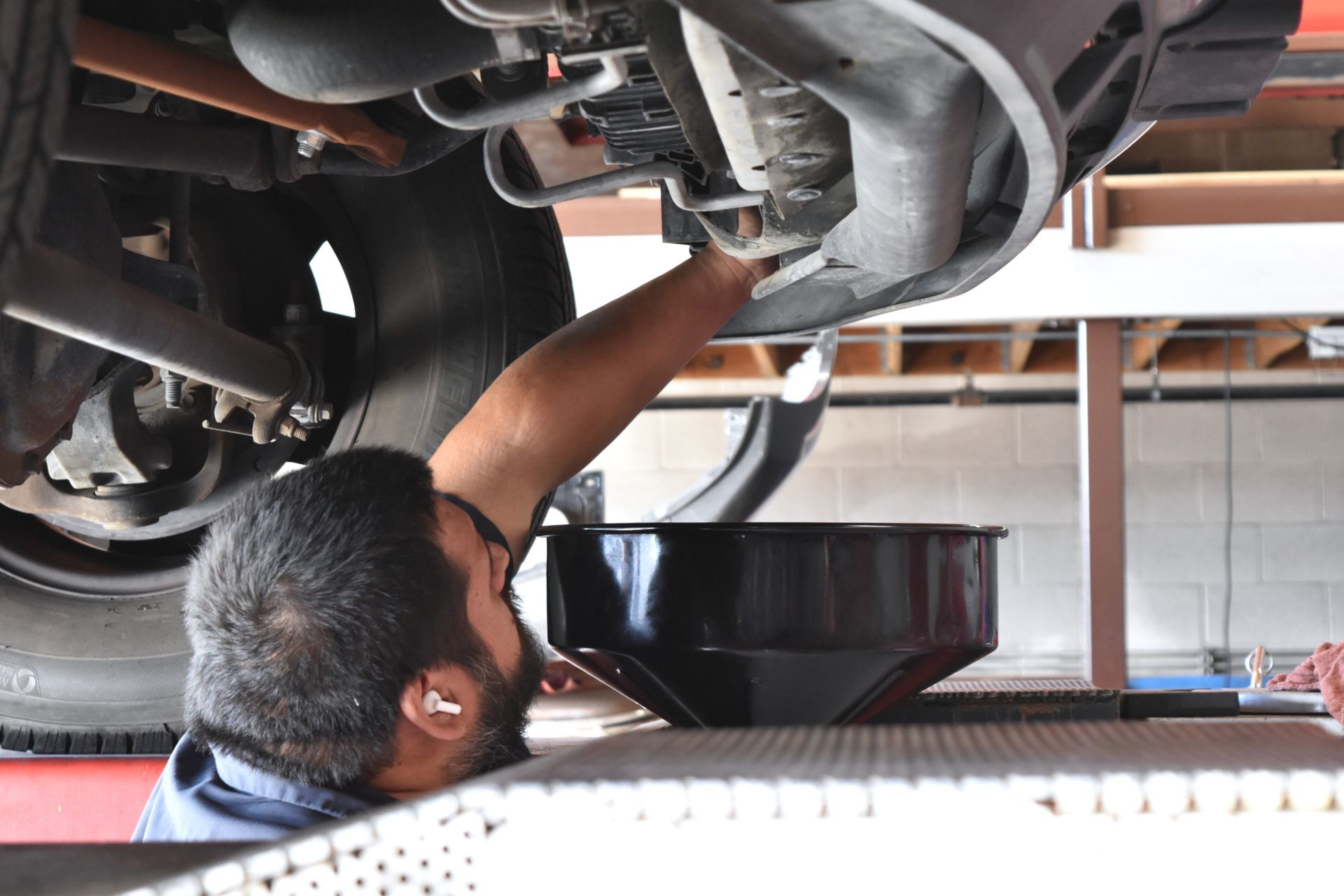 Auto repair technician performing a routine oil change on a vehicle in a service bay