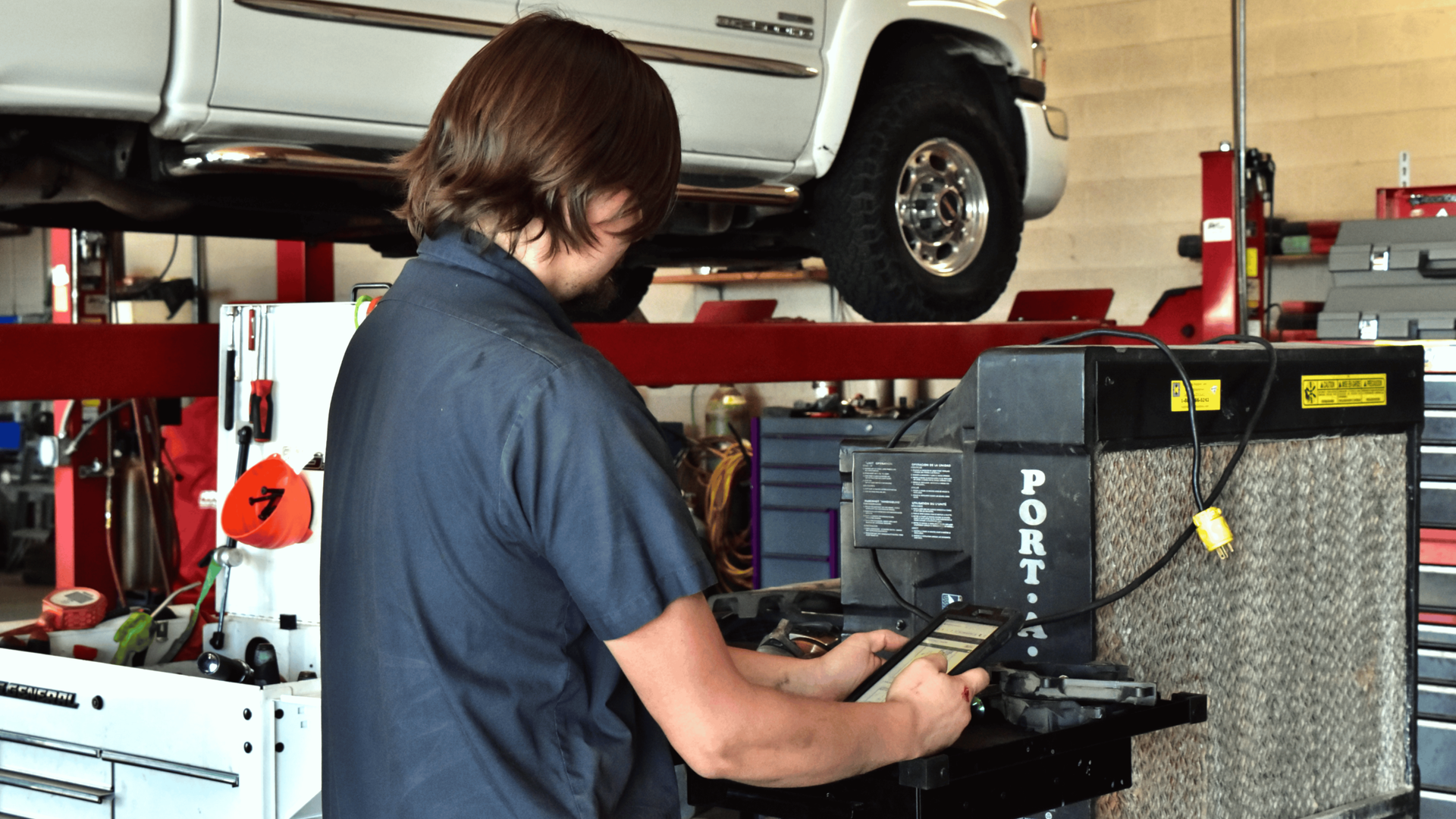 Technician reviewing digital vehicle inspection during Phoenix summer car care service check.