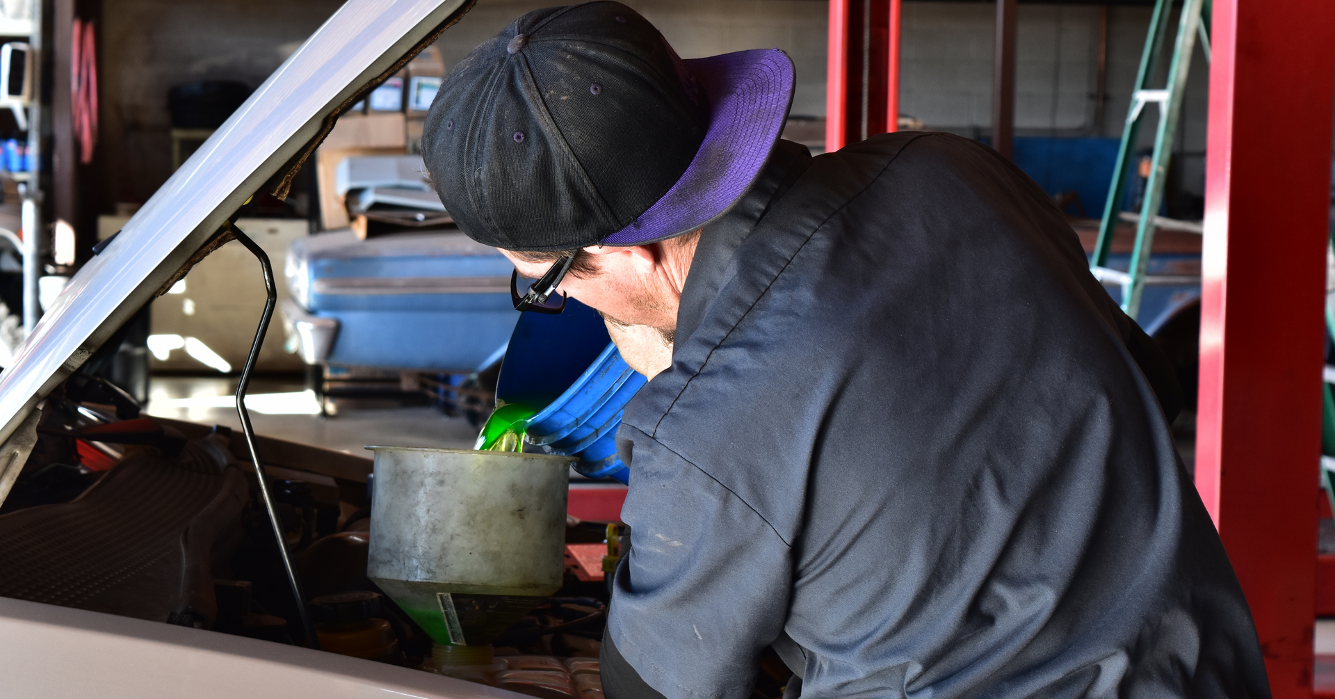 Technician filling coolant during pre road trip inspection in Phoenix to prevent overheating