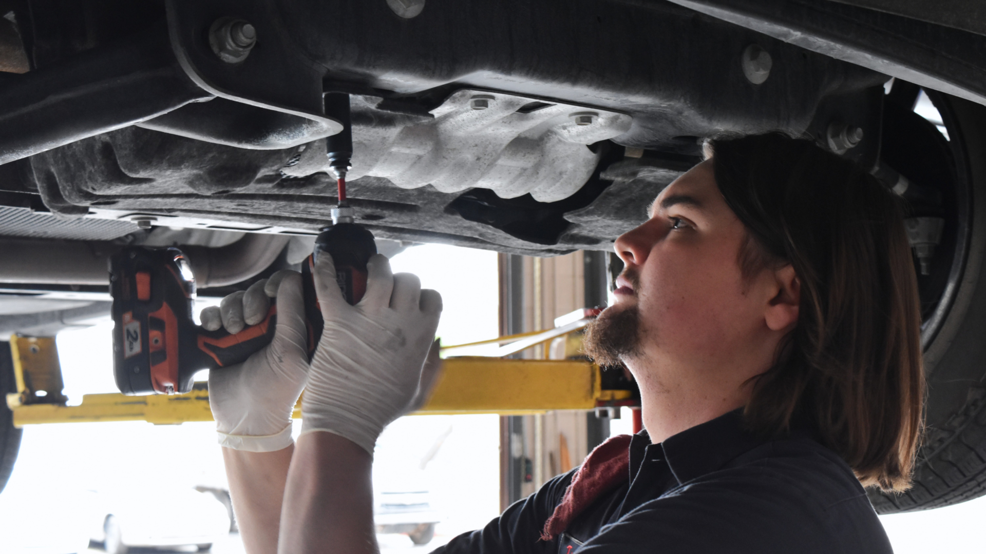 Precision Tire and Auto Center mechanic performing auto repair under a car in Phoenix