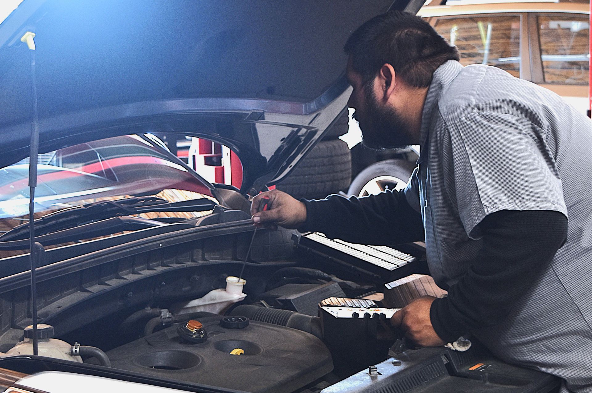 Precision Tire and Auto Center technician inspecting engine components during a tune-up in Phoenix, 