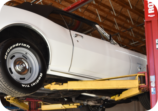 white car on lift | Precision Tire and Auto Center