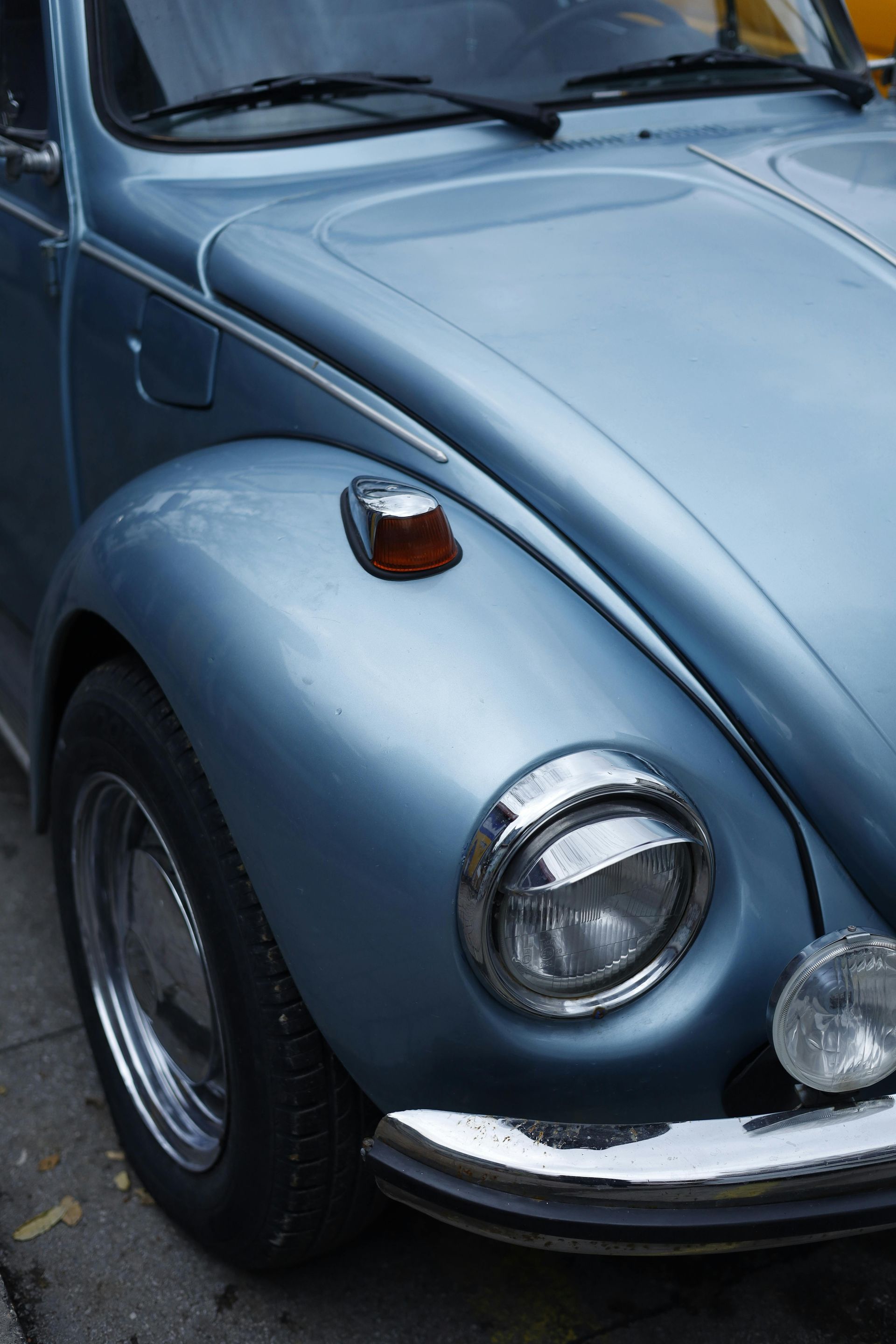 Close-up of a light blue classic Volkswagen Beetle front fender and headlight