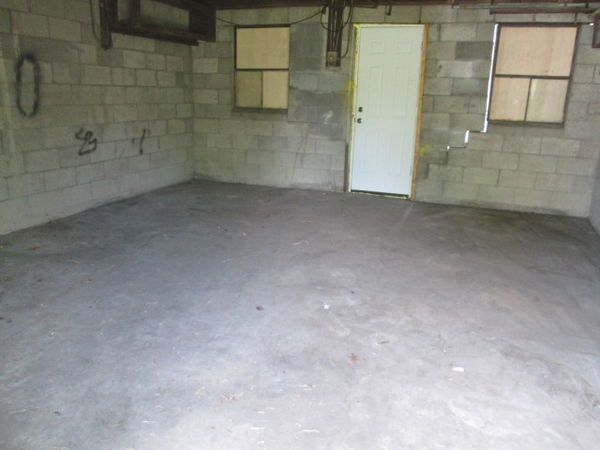 An empty garage with a door and two windows.