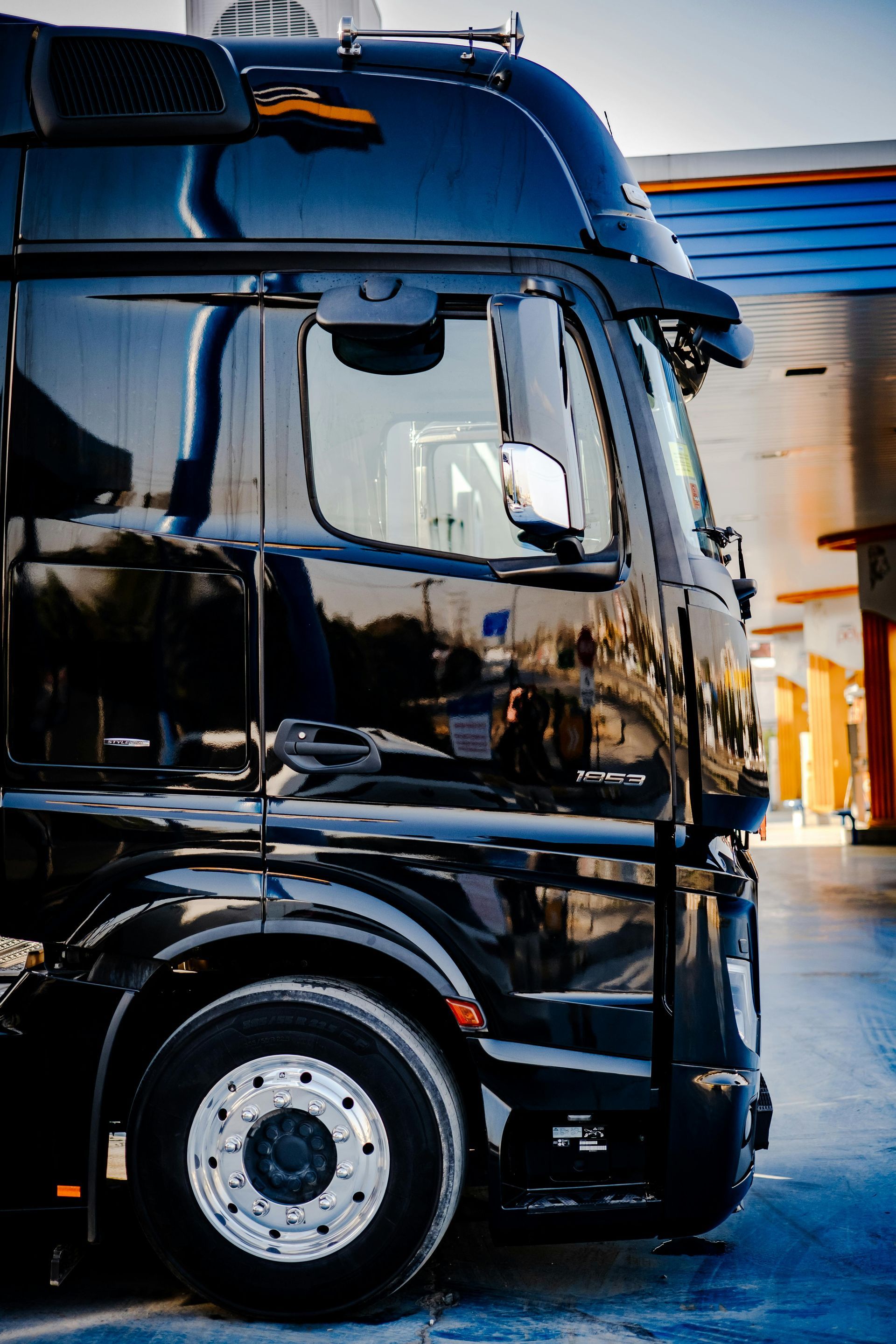 A black semi truck is parked at a gas station.