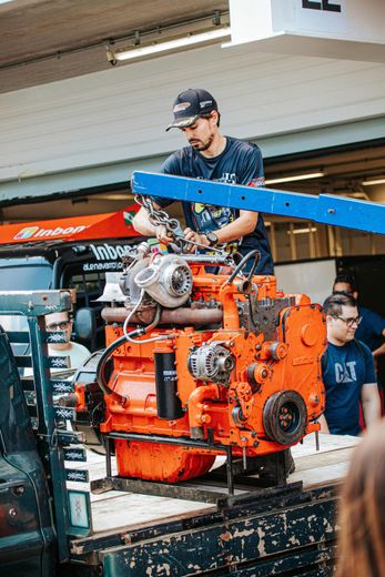 A man is working on a large orange engine on top of a truck.