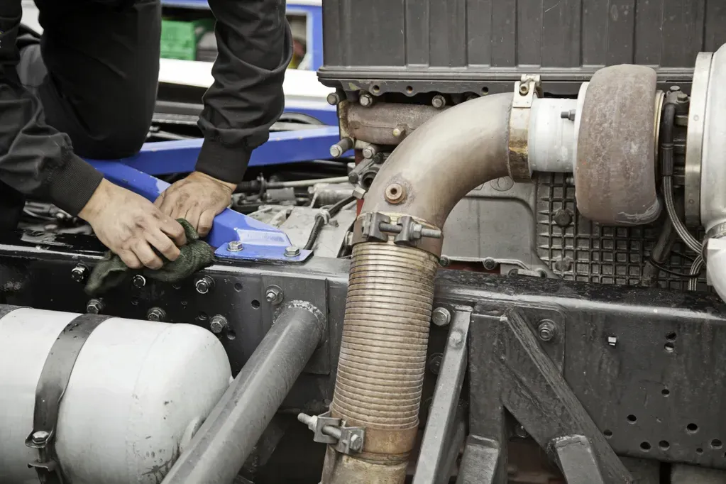 A man is working on the engine of a truck.