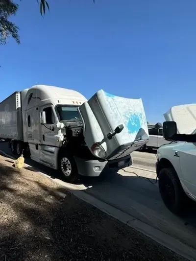A semi truck with its hood open is parked on the side of the road.