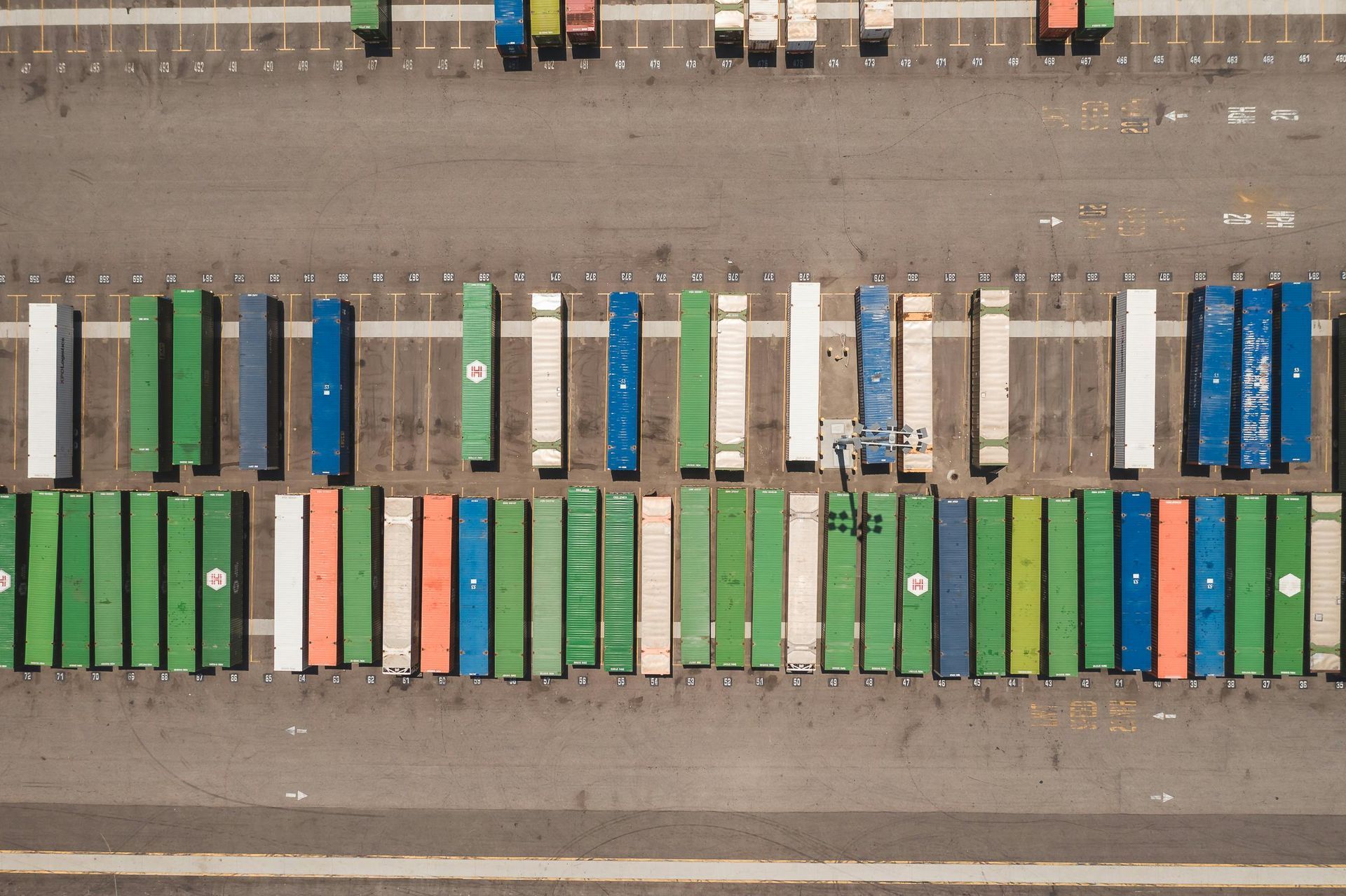 Overhead view of dozens of shipping containers in various colors at a California port container yard