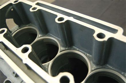 Primer plano de un bloque de motor gris que muestra los cilindros y los orificios de los pernos