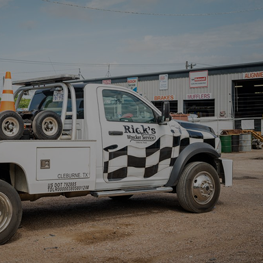 A white tow truck with black checkerboard design | Rick's Automotive