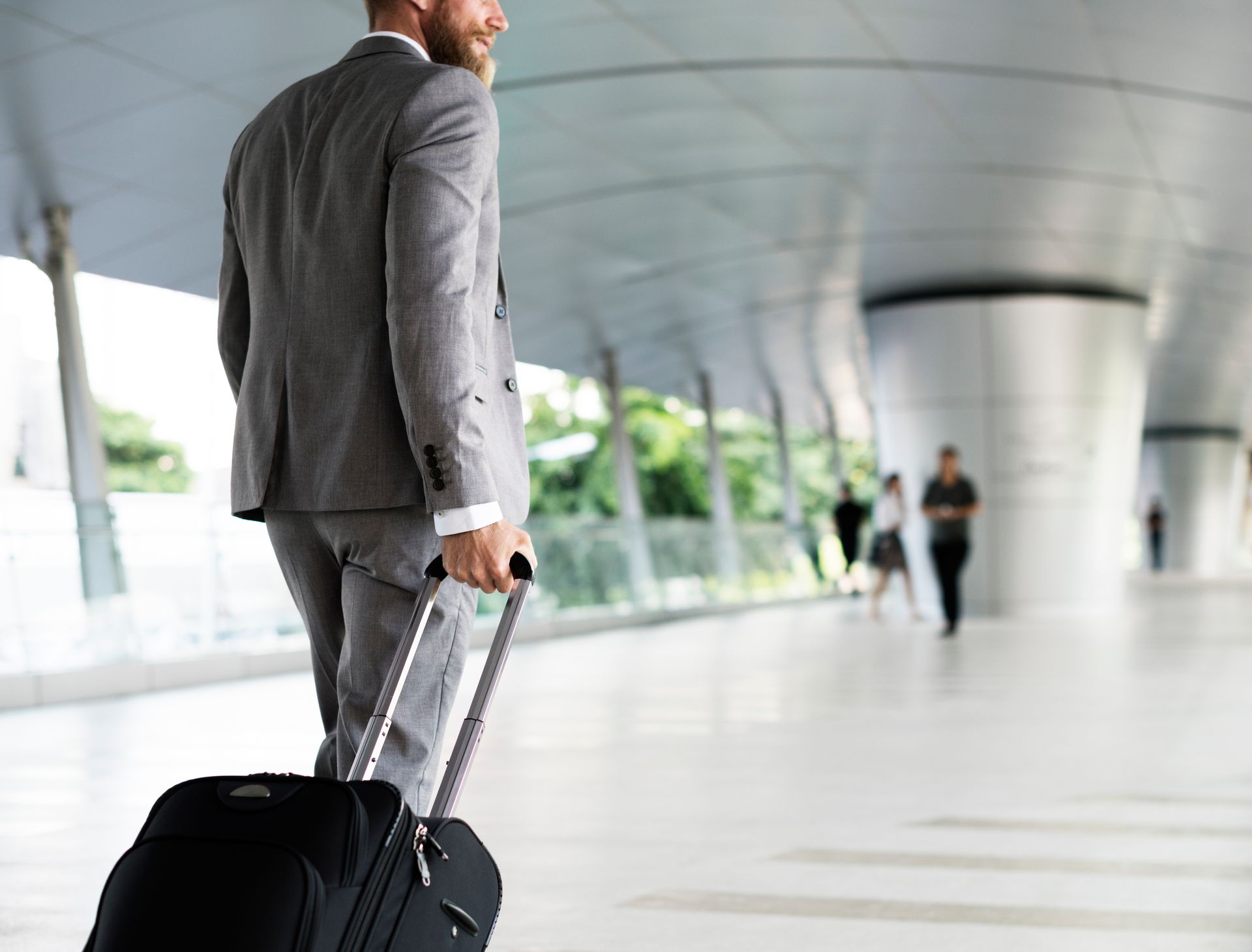 Executive traveler with luggage at a modern international airport terminal – Diplomatic relocation services London
