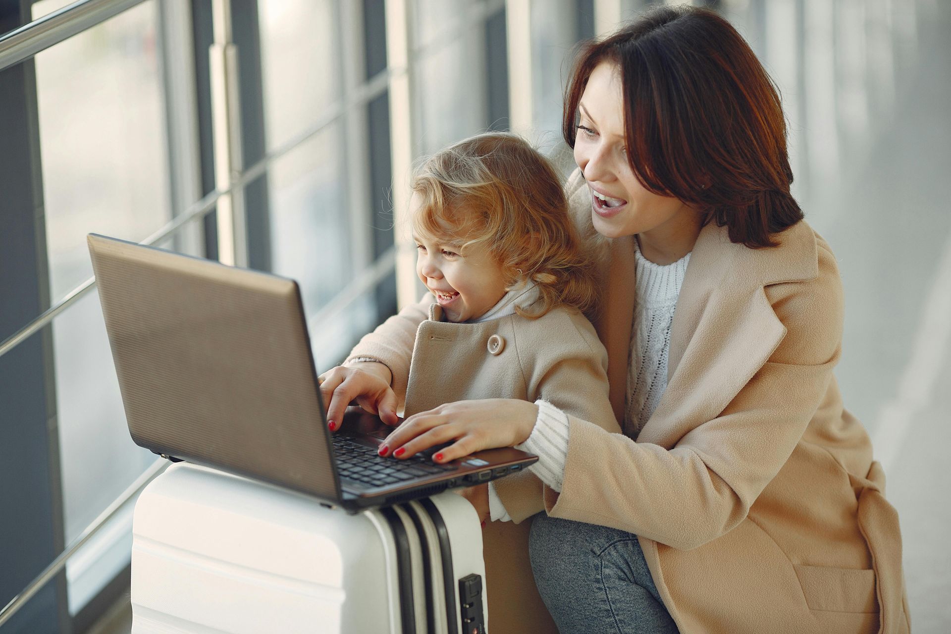 Planning your diplomatic move together — children feel calmer when they're part of the process Mother and young child looking at a laptop together with a suitcase, preparing for an international family relocation