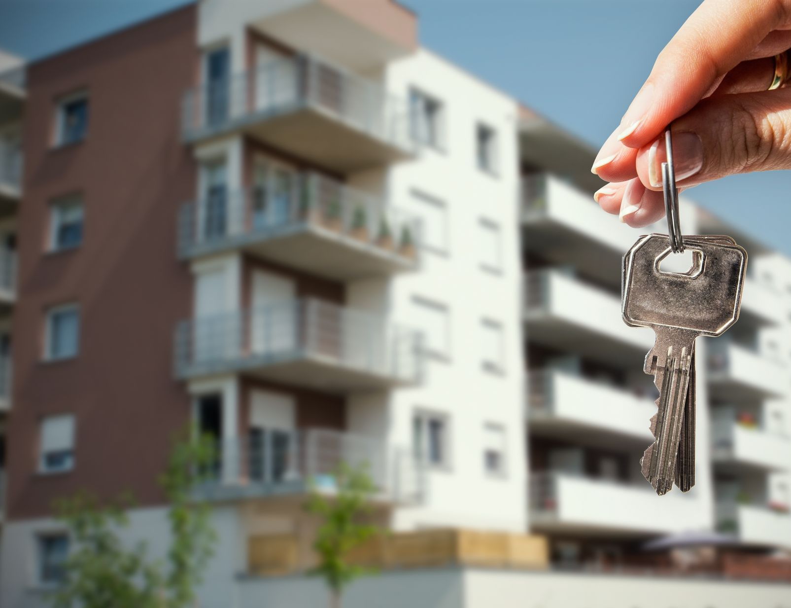 A person is holding a key in front of a building