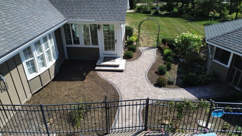 White brick path winds through a green, lush garden toward sunlight.