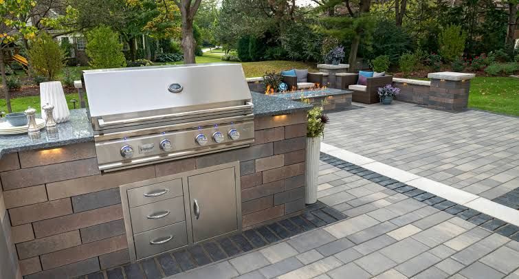Outdoor kitchen with grill, sink, and countertop. Patio with dining set and umbrella.