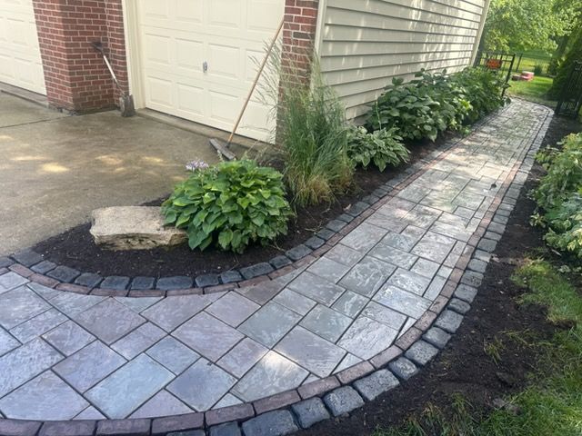 Person in safety gear power washing a brick paved surface.