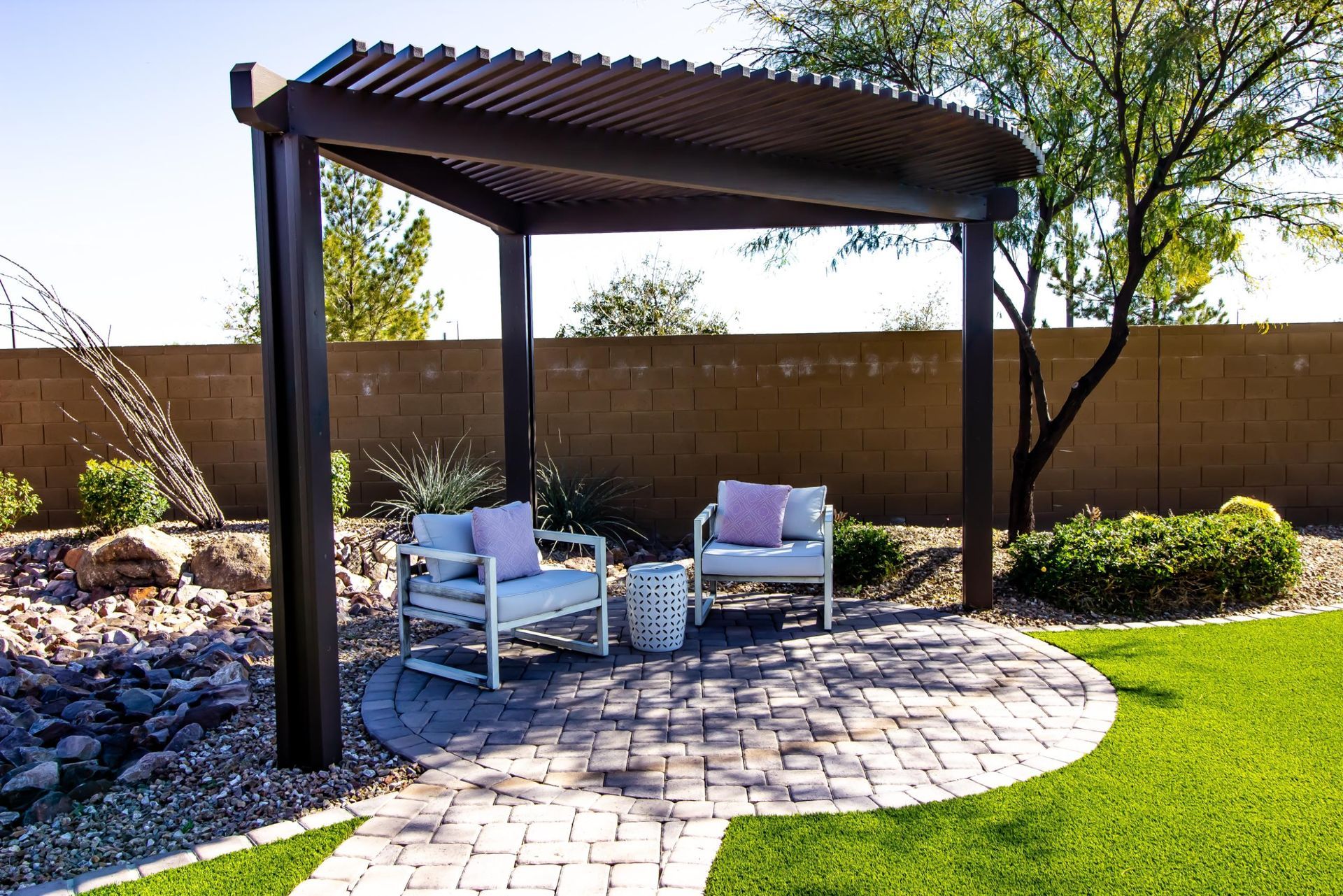 Pergola over a brick patio with seating, in a desert landscape.