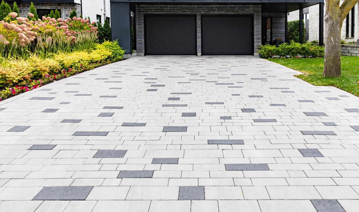 Driveway with light and dark gray pavers leading to a two-car garage.