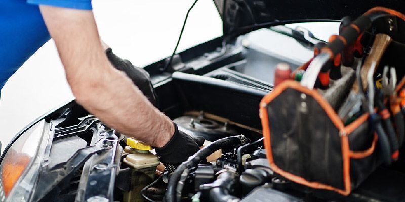 a man is working on the engine of a car .