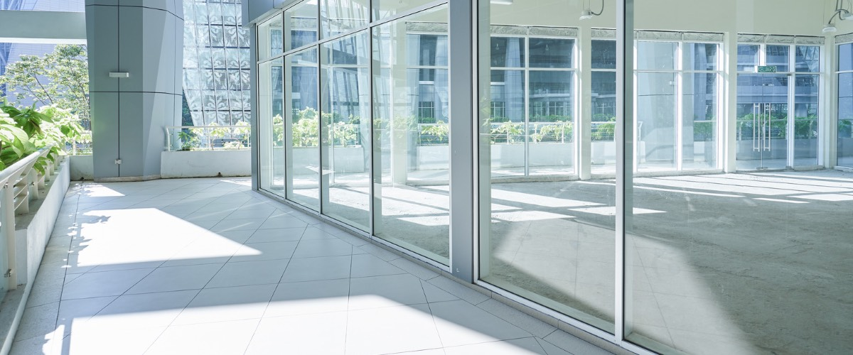 Modern building with glass walls reflecting the outdoor surroundings and sunlight.