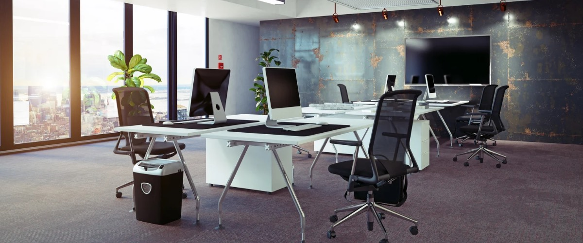 Modern office with desks, chairs, computers, and large windows with a city view.