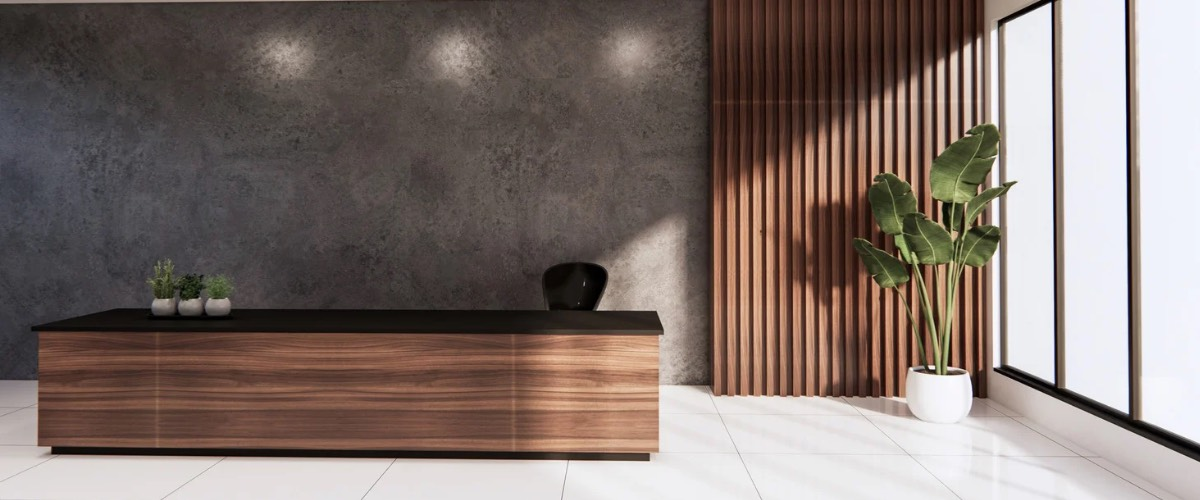 Wooden reception desk with a plant and large windows in a modern office space.