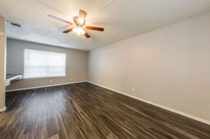 Greenwood Square - laminate grey wood flooring  living room with ceiling fan.