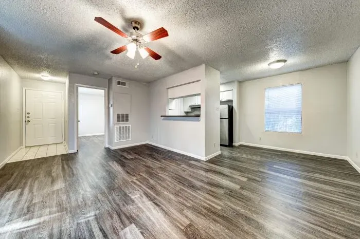 Living room with grey floors and ceiling fan and kitchen