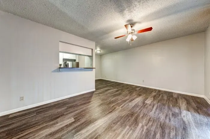 Living room with grey floors and ceiling fan and kitchen