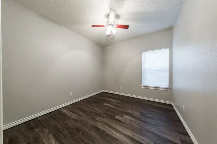 Three Villas - bedroom with grey laminate flooring and ceiling fan.