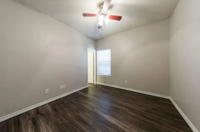 Three Villas - bedroom with grey laminate flooring and ceiling fan.