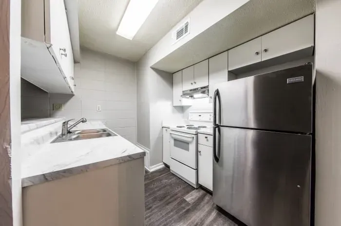 The Colony -  kitchen with grey laminate wood flooring  and stainless steel refrigerator and white stove