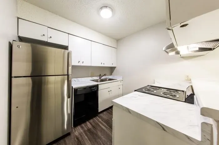 The Colony -  kitchen with grey laminate wood flooring  and stainless steel refrigerator and white stove