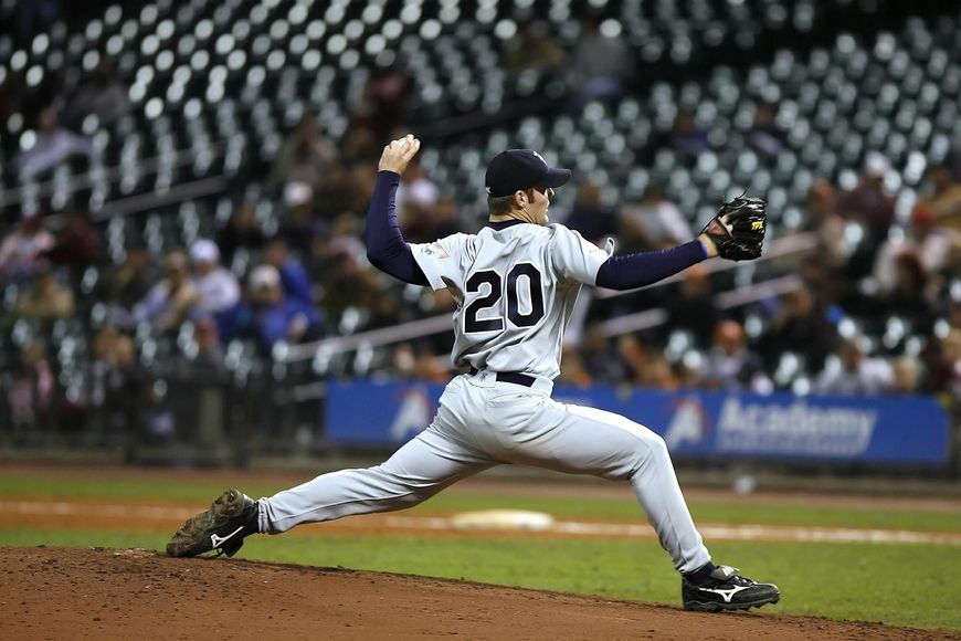 A baseball player with the number 20 on his back is pitching the ball.