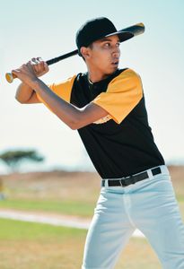 A man in a black and yellow baseball uniform is swinging a bat.