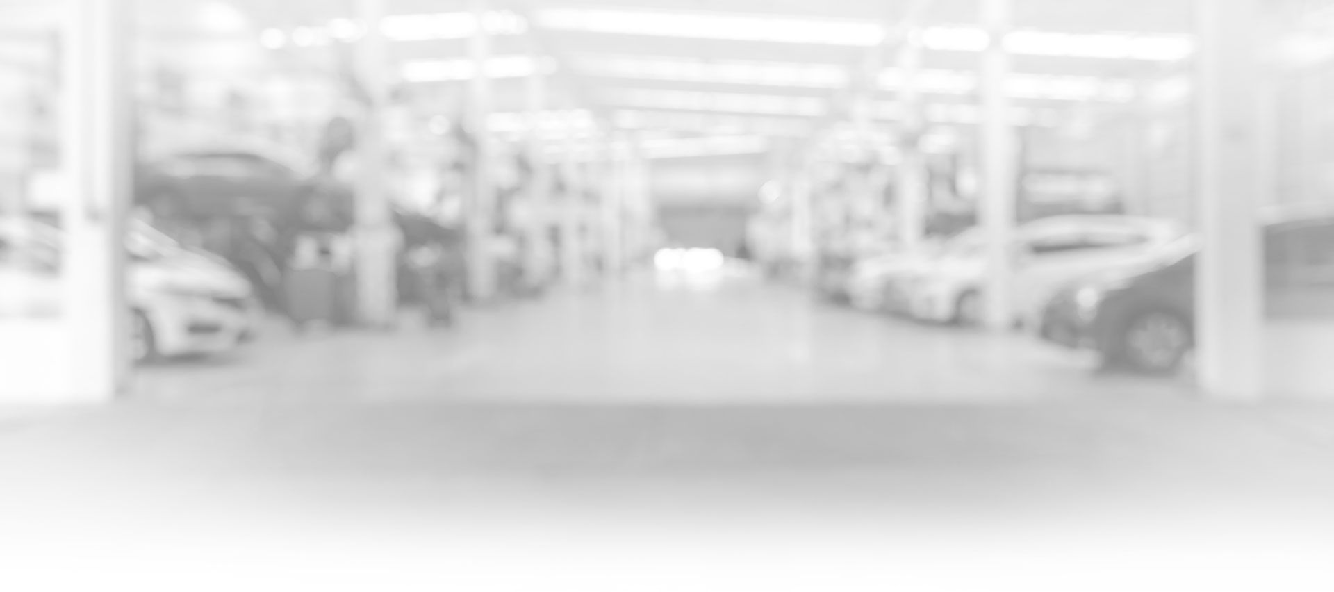Blurred view inside a car repair shop with vehicles parked in rows. | Louis Garage, Inc.