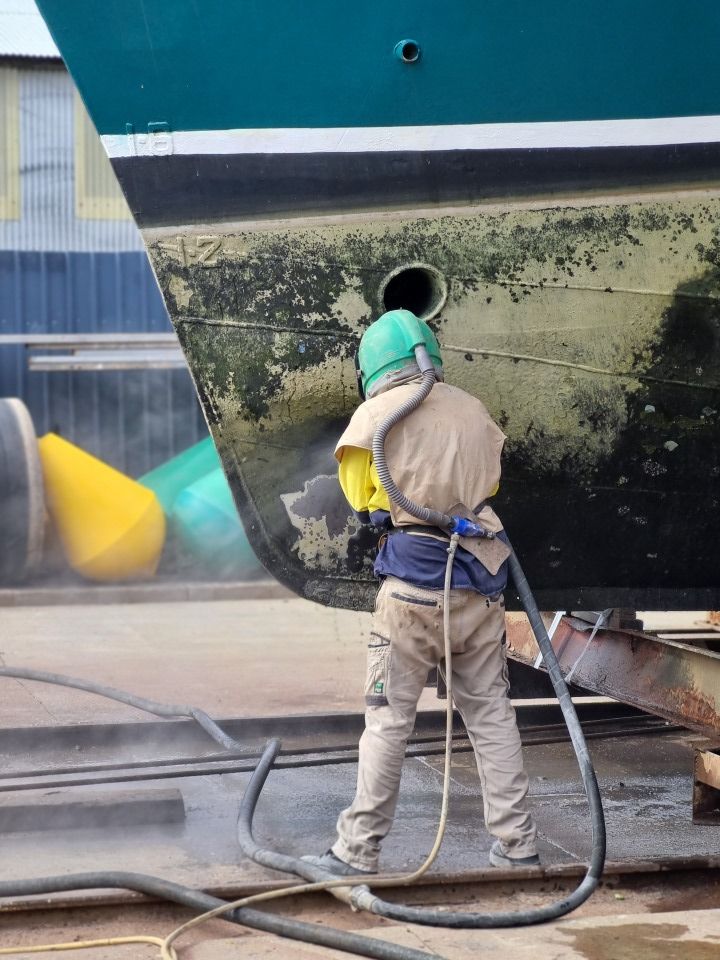 A Man is Sandblasting the Side of a Boat — Goat Collective in Tintenbar, NSW